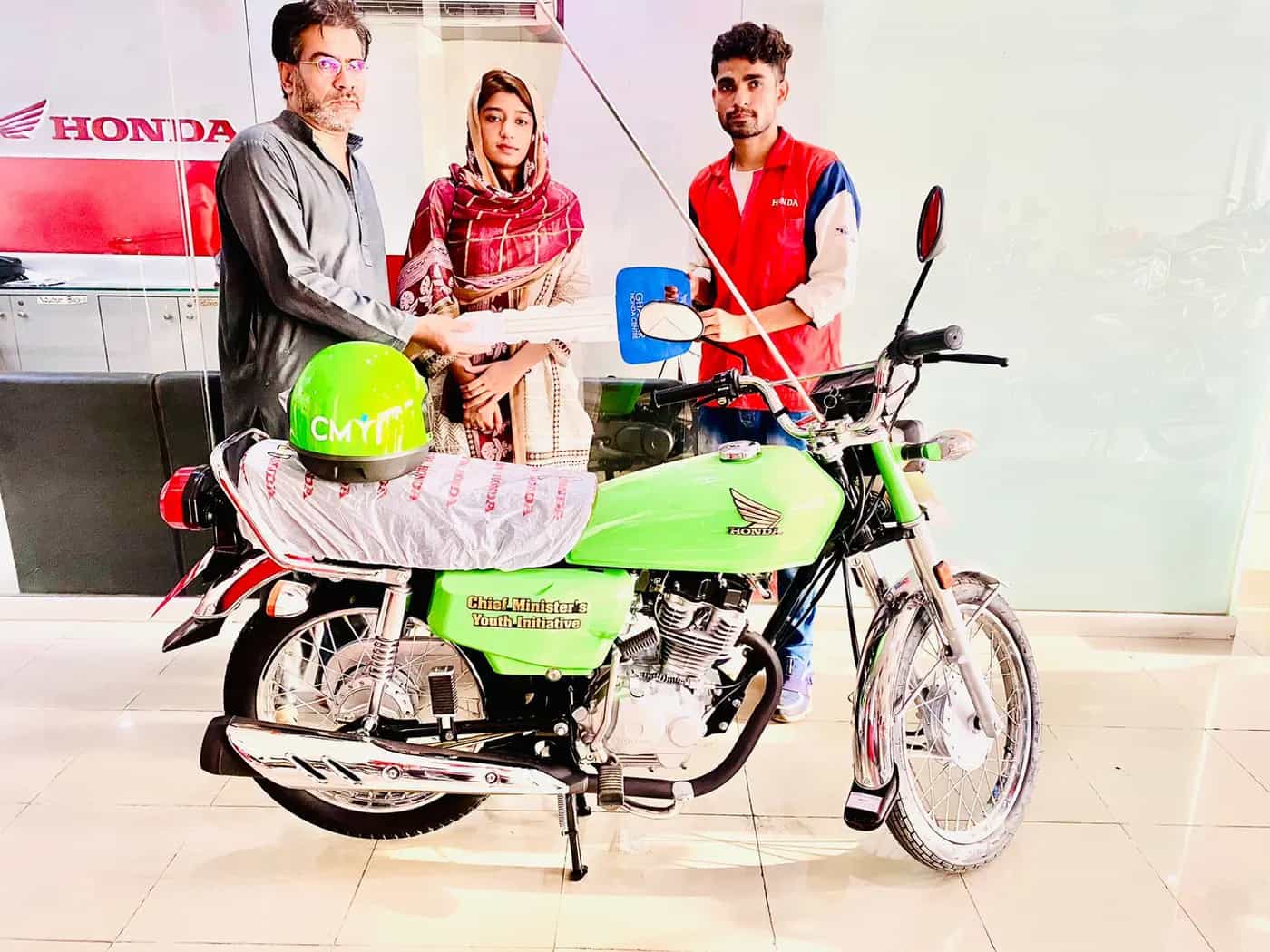 A successful female applicant receiving her bike documents at the dealership counter