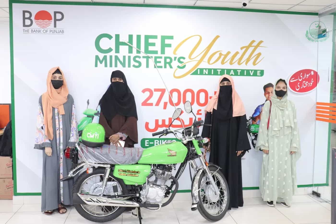 Scheme beneficiaries with their new green bikes outside the dealership