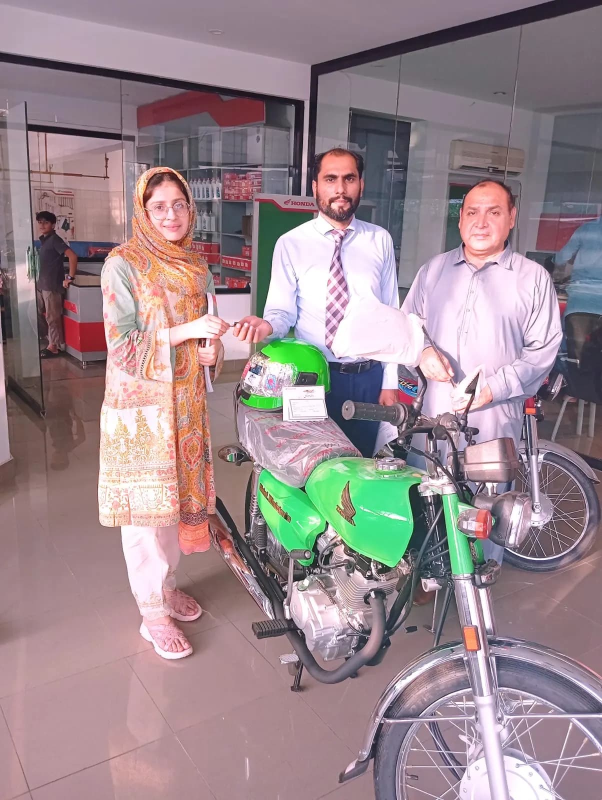A female beneficiary with her new scheme bike outside the dealership